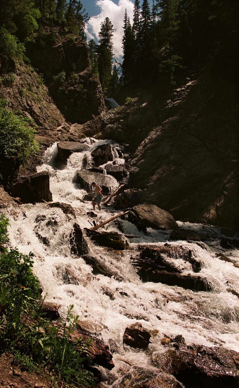 On July 2, 1999, a hiker wades across a shallow section of Donut Falls during a short day hike. Located nine miles east up Big Cottonwood Canyon, Donut Falls offers an easy hike for families with scenic views.