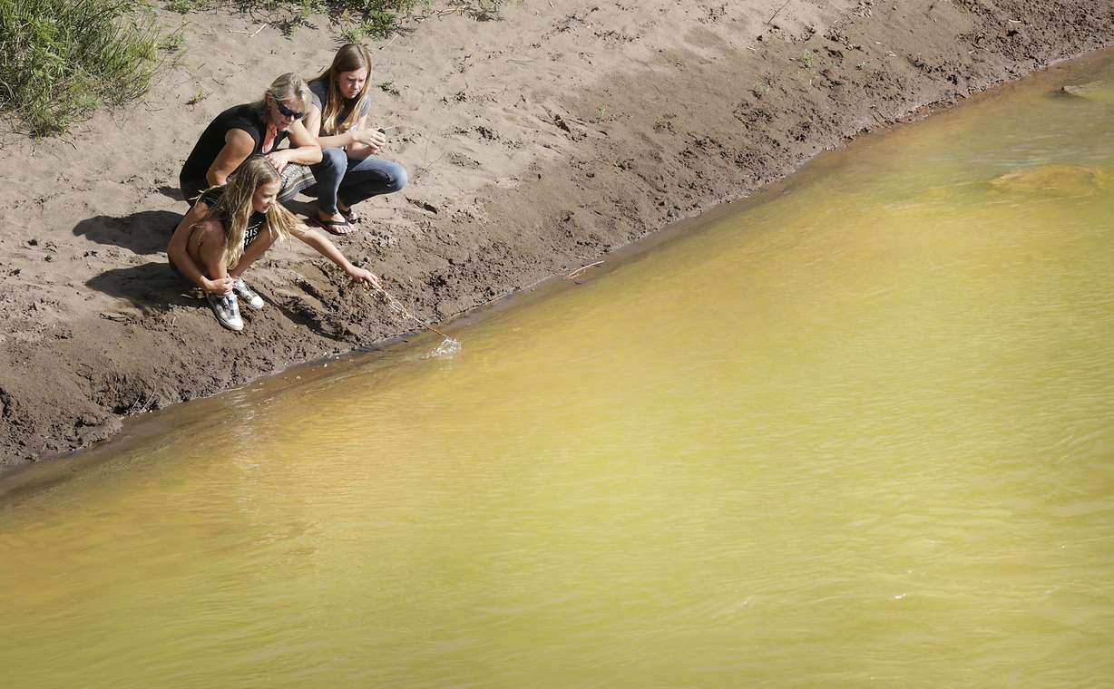 Kim Cofman and her daughters Acacia, 12, left, and Cayenne, 14, try to stir up sludge from the Gold King Mine that covers the bottom the Animas River on Saturday, Aug. 8, 2015, in Durango, Colo. Photo: AP Photo