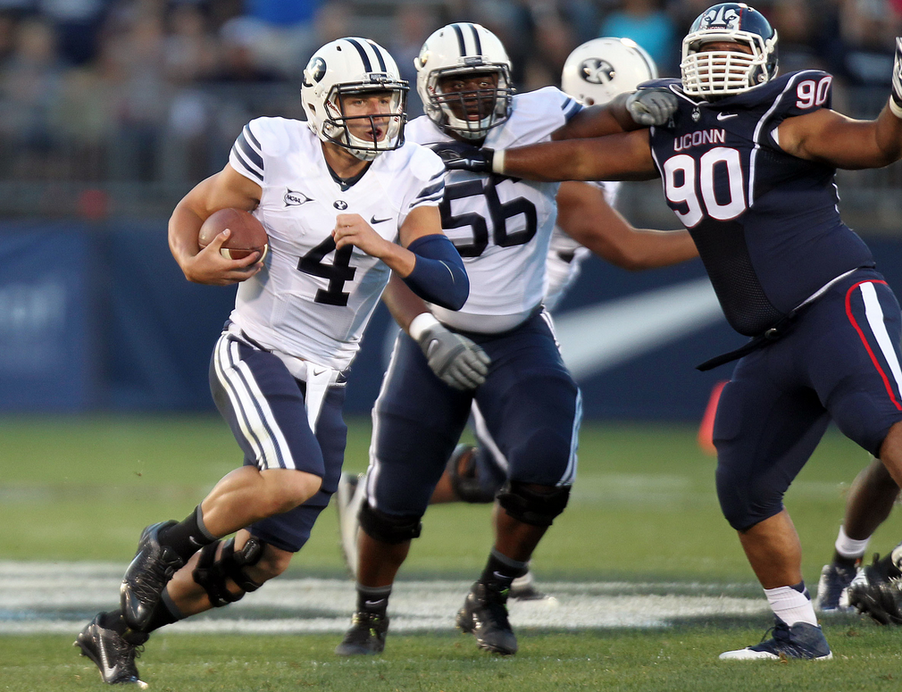 BYU quarterback Taysom Hill (4) runs past BYU offensive linesman Tejan Koroma (56) and Connecticut Huskies defensive tackle Julian Campenni (90) during a football game at Rentschler Field in East Hartford, Conn., Aug. 29, 2014. (Photo: Kristin Murphy/Deseret News)