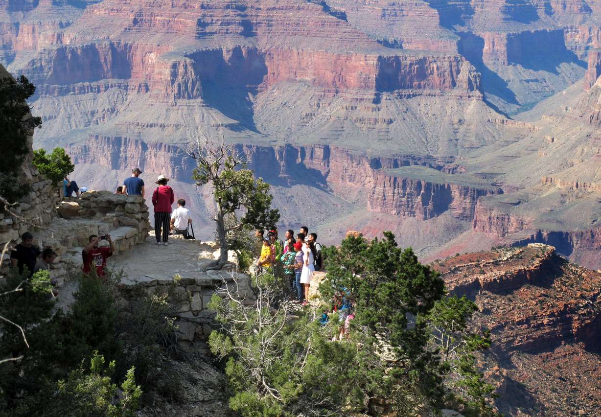 In this Wednesday, Aug. 19, 2015 photo, visitors gather at an outlook on the South Rim of Grand Canyon National Park in northern Arizona. The Grand Canyon and other big national parks are seeing more visitors than usual this year, partly driven by good weather, cheap gas and marketing campaigns. (AP Photo/Felicia Fonseca)