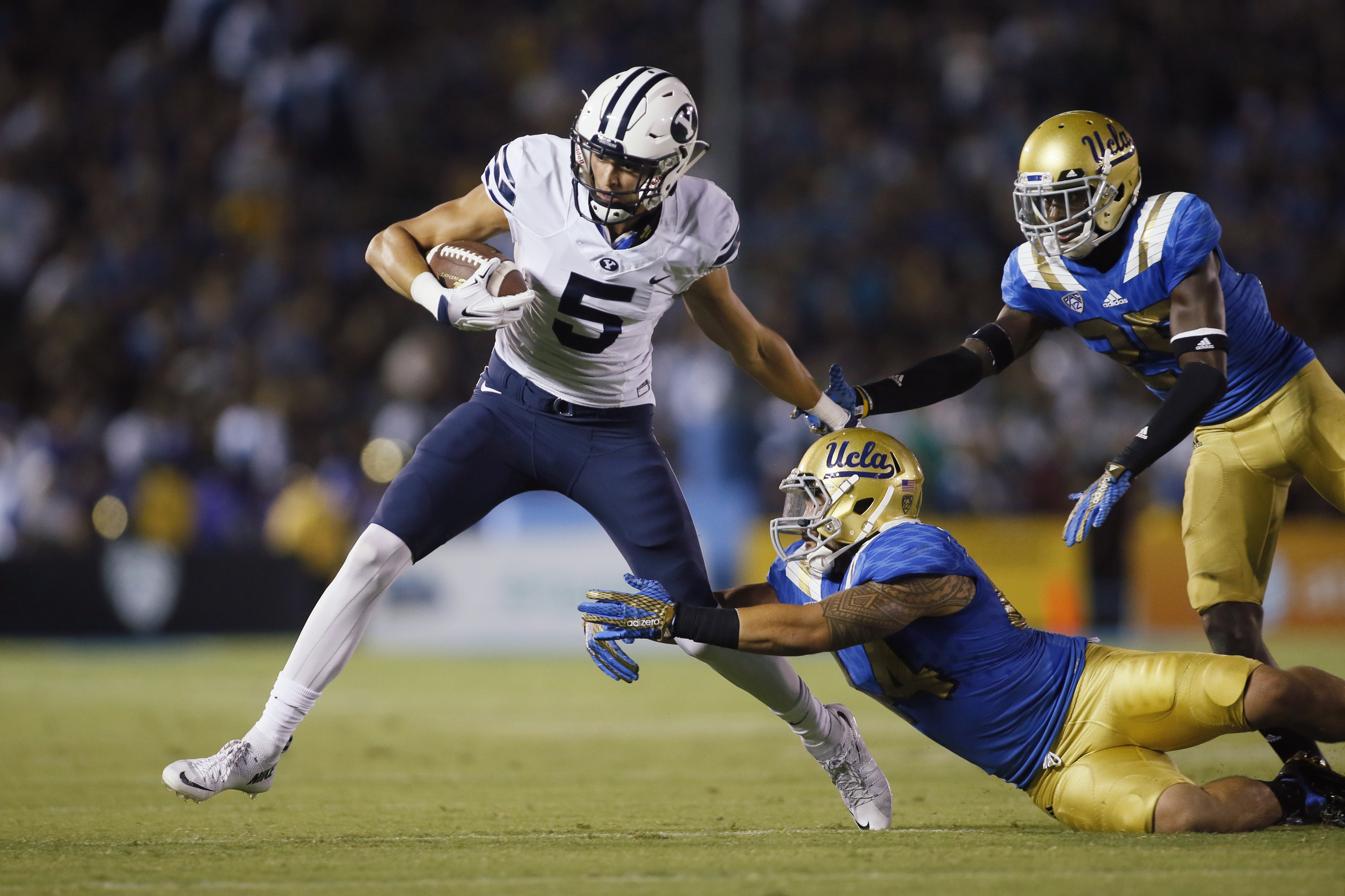 BYU wide receiver Nick Kurtz tries to avoid UCLA linebacker Isaako Savaiinaea, center, and defensive back Denzel Fisher, right, after a reception during the first half of an NCAA college football game, Saturday, Sept. 19, 2015, in Pasadena, California. (AP Photo/Danny Moloshok)