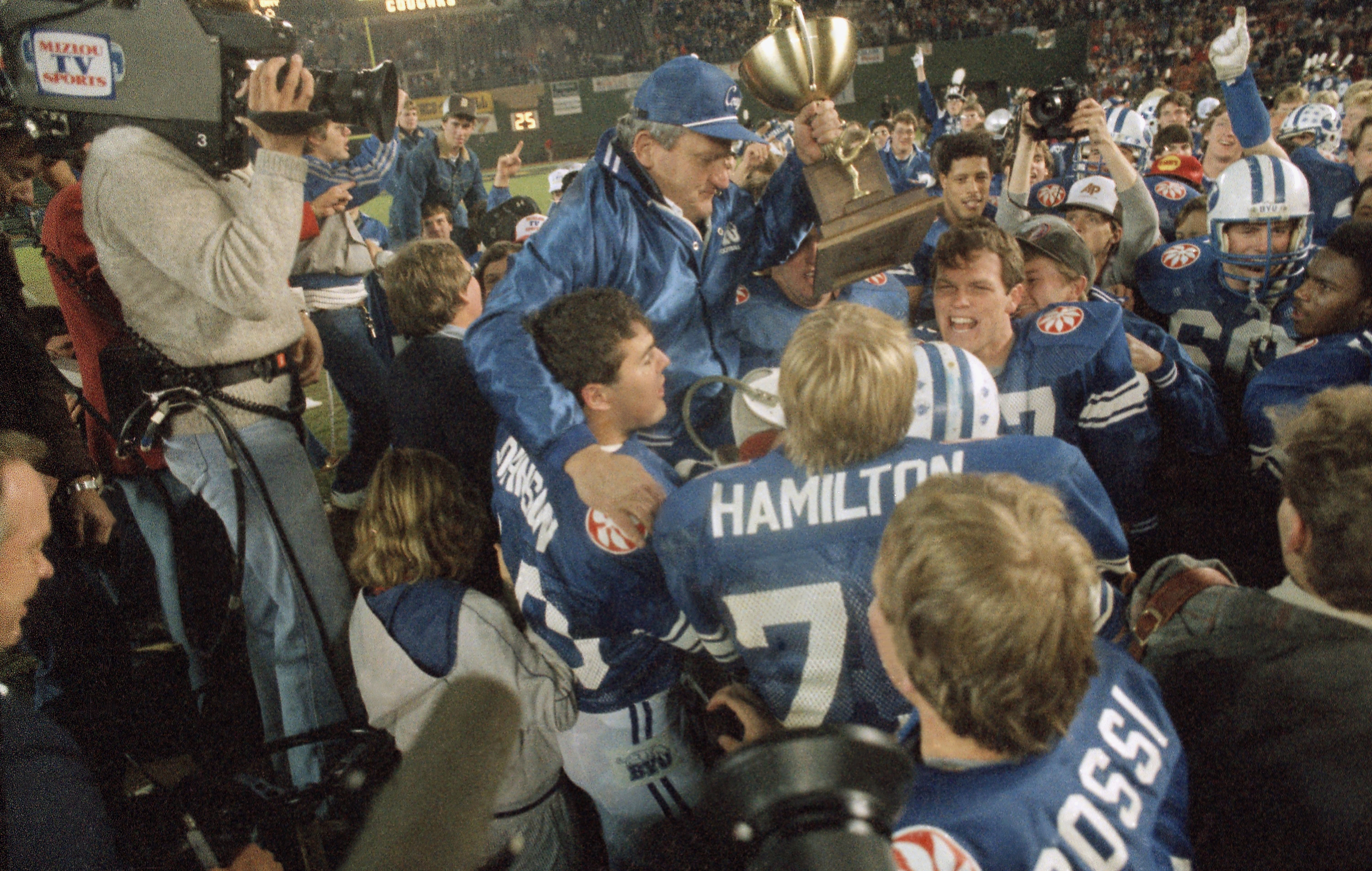 BYU Holiday Bowl 1984 Brigham Young University football coach LaVell Edwards carries the trophy as he is carried off the field following BYU's 24-17 victory over the University of Michigan in the Holiday Bowl, Dec. 22, 1984 in San Diego. (AP Photo/Phillip Davies)