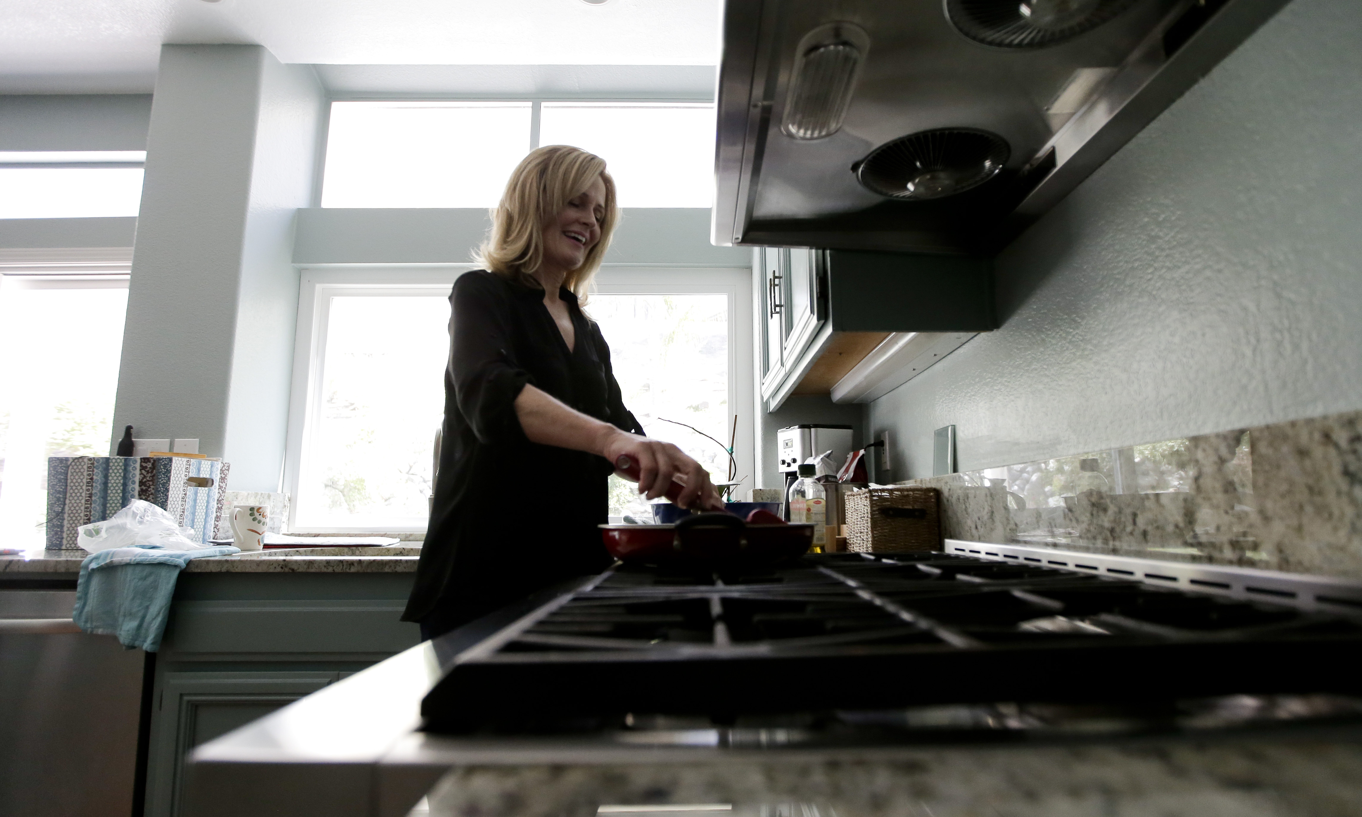 In this July 10, 2015 photo, Jill Rosales, married to Ernie Rosales, works in the kitchen of their home in Temecula, Calif. "Neither of us really likes debt," she said. "But to some degree in the United States, it's just a part of living here. There's some debt that you have to take on to get ahead." (AP Photo/Chris Carlson)