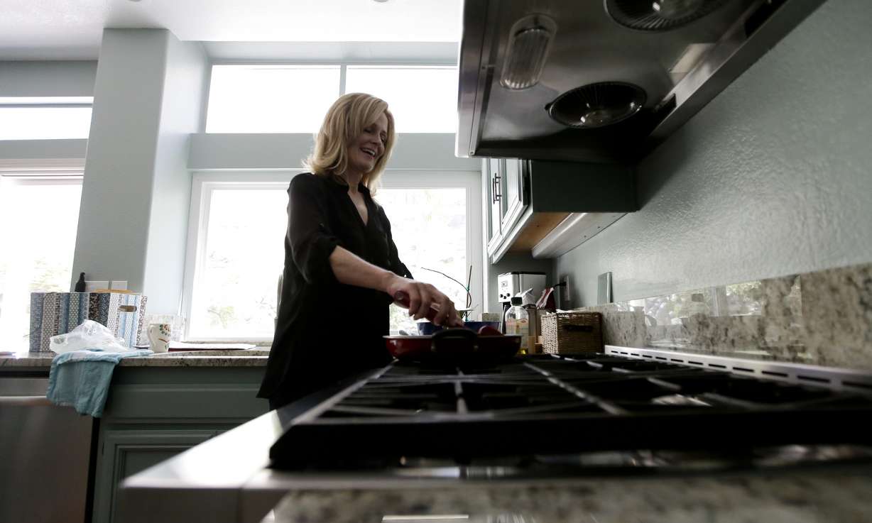 In this July 10, 2015 photo, Jill Rosales, married to Ernie Rosales, works in the kitchen of their home in Temecula, Calif. "Neither of us really likes debt," she said. "But to some degree in the United States, it's just a part of living here. There's some debt that you have to take on to get ahead." (AP Photo/Chris Carlson)