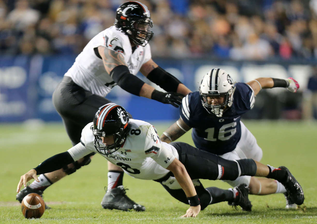 Cincinnati Bearcats quarterback Hayden Moore reaches for the ball after dropping it during a pass-off in a football game agaisnt BYU at the LaVell Edwards Stadium in Provo Friday, Oct. 16, 2015. Brigham Young Cougars linebacker Sione Takitaki (16) dives for the tackle. (Kristin Murphy/Deseret News)