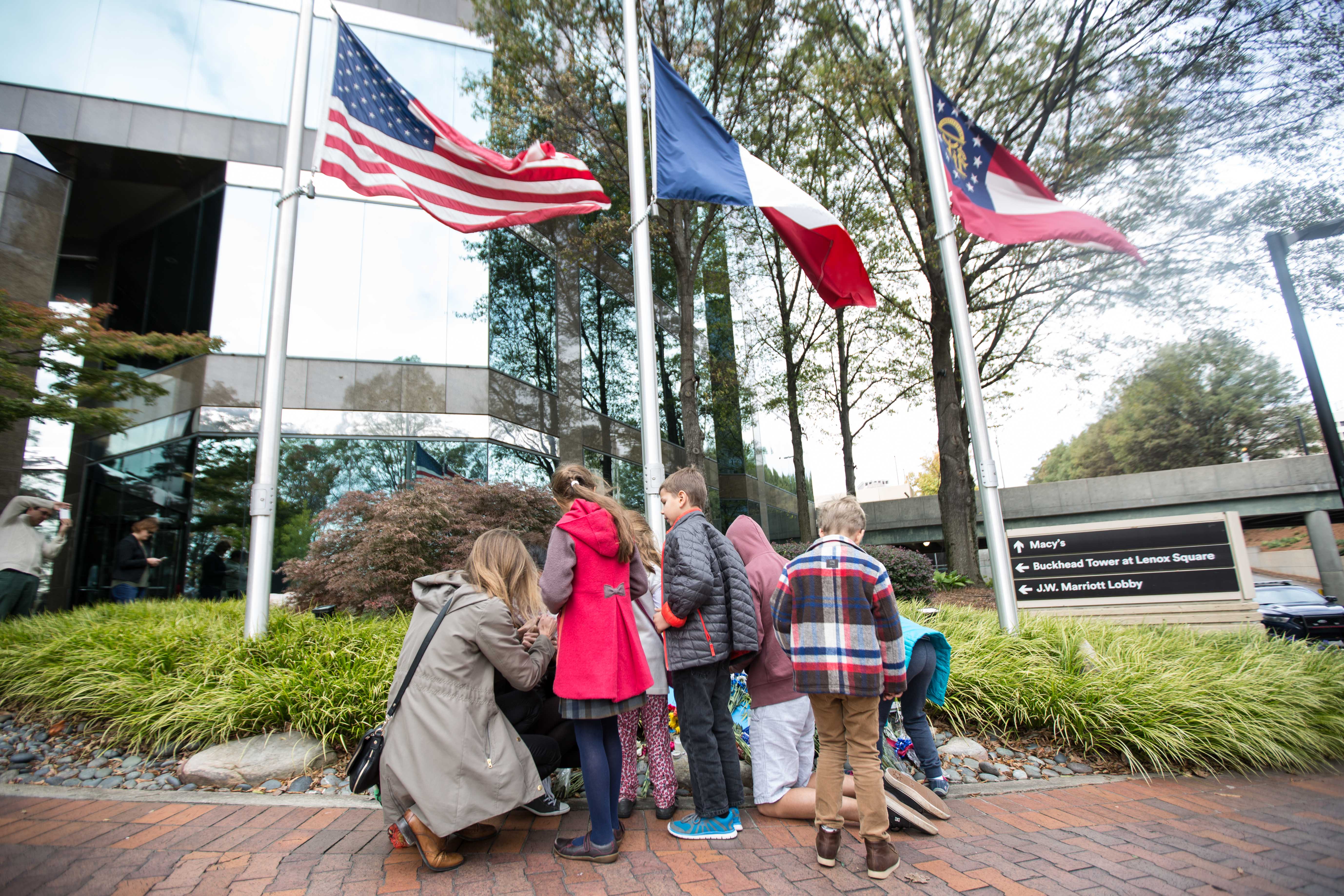 People gather around a makeshift memorial outside at the Consulate General of France Sunday, Nov. 15, 2015, in Atlanta. Multiple attacks across Paris on Friday night have left scores dead and hundreds injured. (AP Photo/Branden Camp)