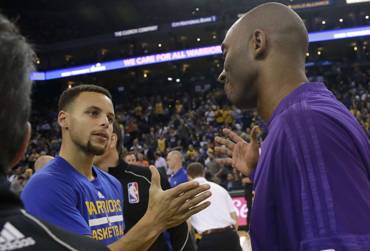 Golden State Warriors guard Stephen Curry, left, greets Los Angeles Lakers guard Kobe Bryant before an NBA basketball game in Oakland, Calif., Tuesday, Nov. 24, 2015. (AP Photo/Jeff Chiu)