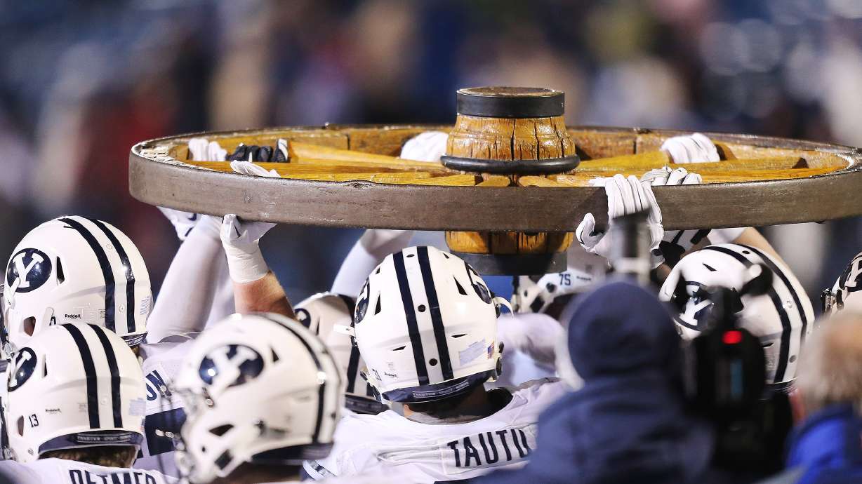 Brigham Young Cougars carry the Old Wagon Wheel after beating USU in Logan Saturday, Nov. 28, 2015. BYU won 51-28.