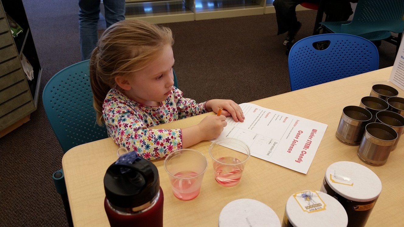 A young library patron writes down her findings from the candy cane science activity. (Photo: Jennifer McKague)