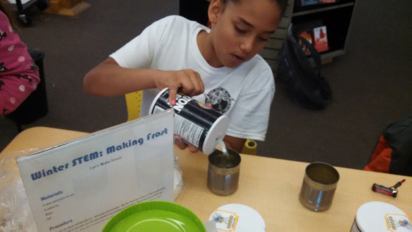A library program participant makes frost for a holiday STEM experiment. (Photo: Jennifer McKague)