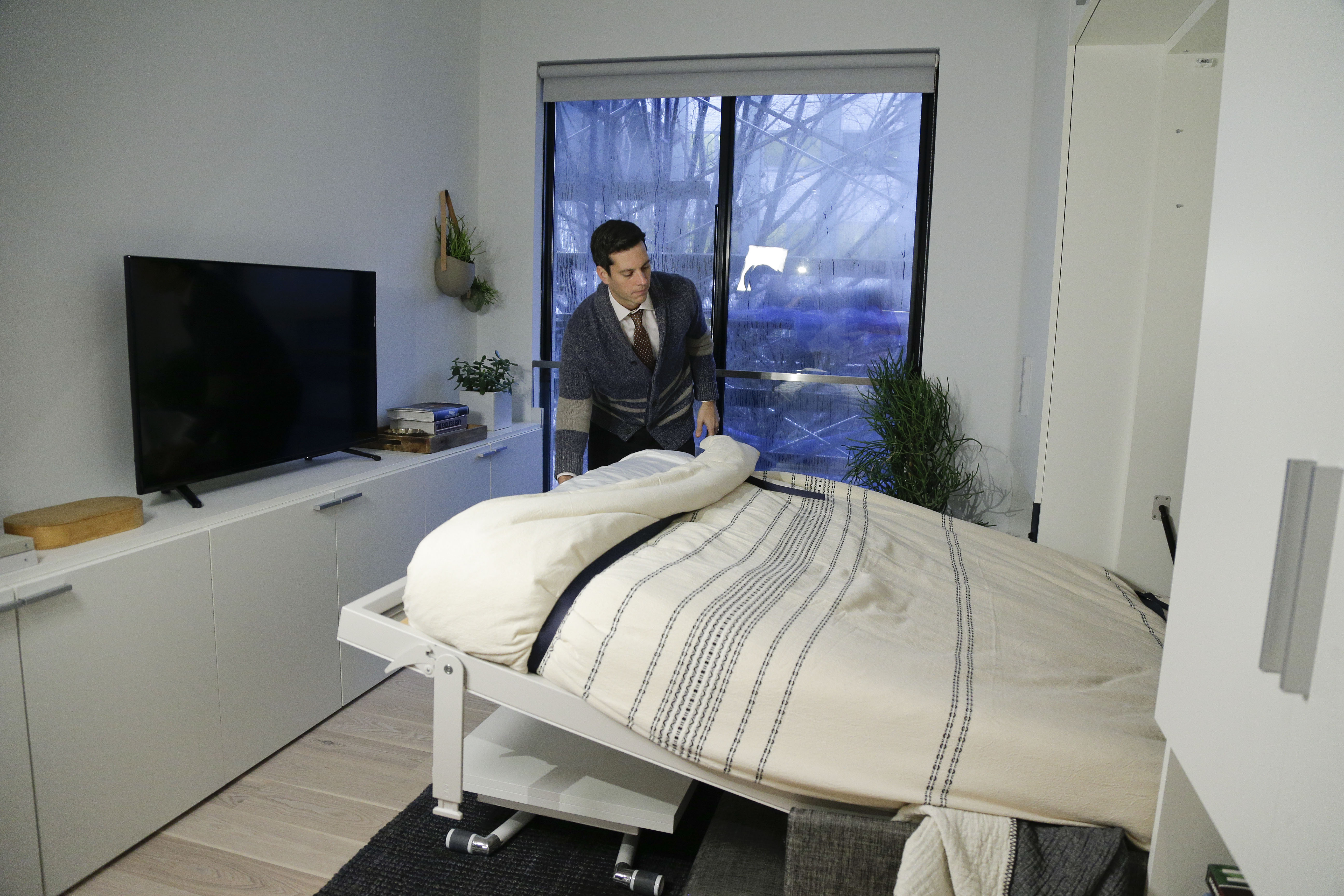 In this Dec. 22, 2015 photo, Stage 3 Properties co-founder Christopher Bledsoe demonstrates a retractable bed that turns into a sofa when stored inside one of the apartment units at the Carmel Place building in New York. (Photo: Julie Jacobsen/AP Photo)