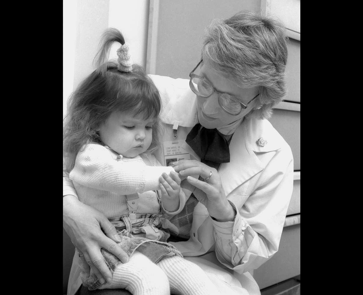 In this June 1988 photo provided by Children's Hospital of Wisconsin, Lynn Bartos, pediatric nurse for Children's Hospital of Wisconsin Gastroenterology Clinic, holds Nicole Frye, left, at Children's Hospital of Wisconsin in Wauwatosa, Wis. The nurse and family were featured on the cover of the hospital's nursing magazine in 1988 for a story about long term care. Bartos and Nicole Krahn, once Frye, recently reunited after about 25 years, with Krahn now taking care of Bartos, who has rheumatoid arthritis. (Jeff Surges/Children's Hospital of Wisconsin via AP)