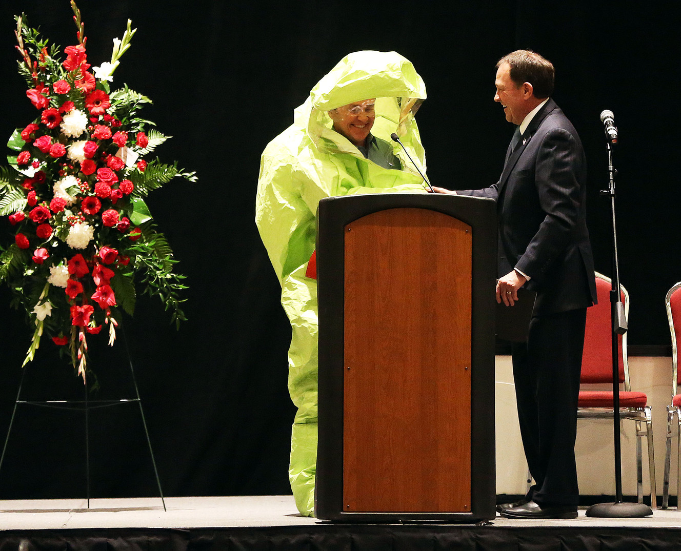 Salt Lake County Councilman Michael Jensen dresses in a hazmat suit as he speaks during a memorial service for Randy Horiuchi in Salt Lake City, Friday, Jan. 15, 2016. This referenced a time Horiuchi dressed in a hazmat suit for an event. At right is Gov. Gary Herbert. (Photo: Ravell Call, Deseret News)