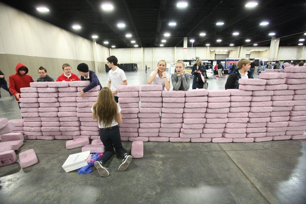 Students build, then destroy, a wall with pink bricks. (Photo: Utah STEM Fest)