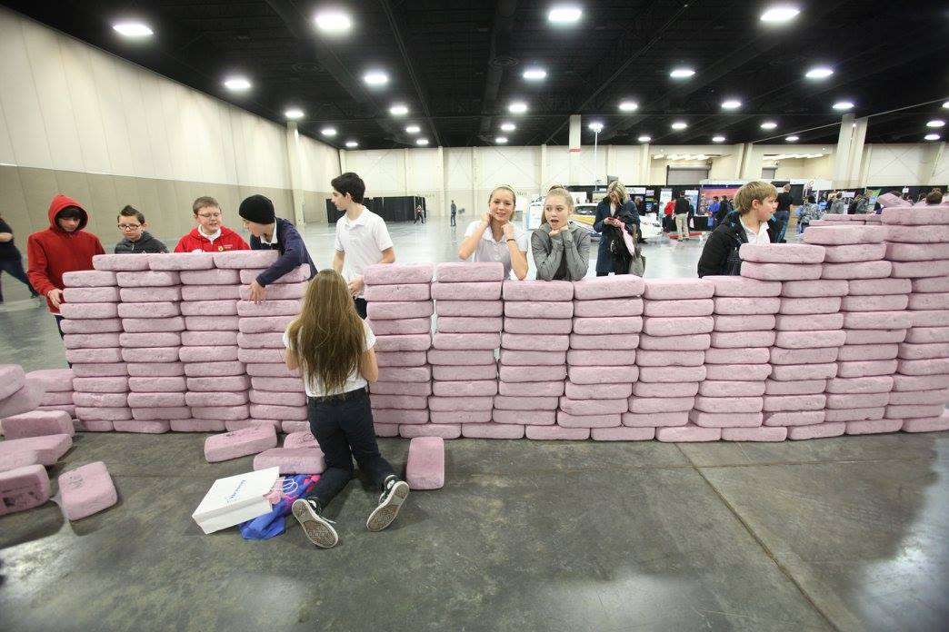 Students build, then destroy, a wall with pink bricks. (Photo: Utah STEM Fest)