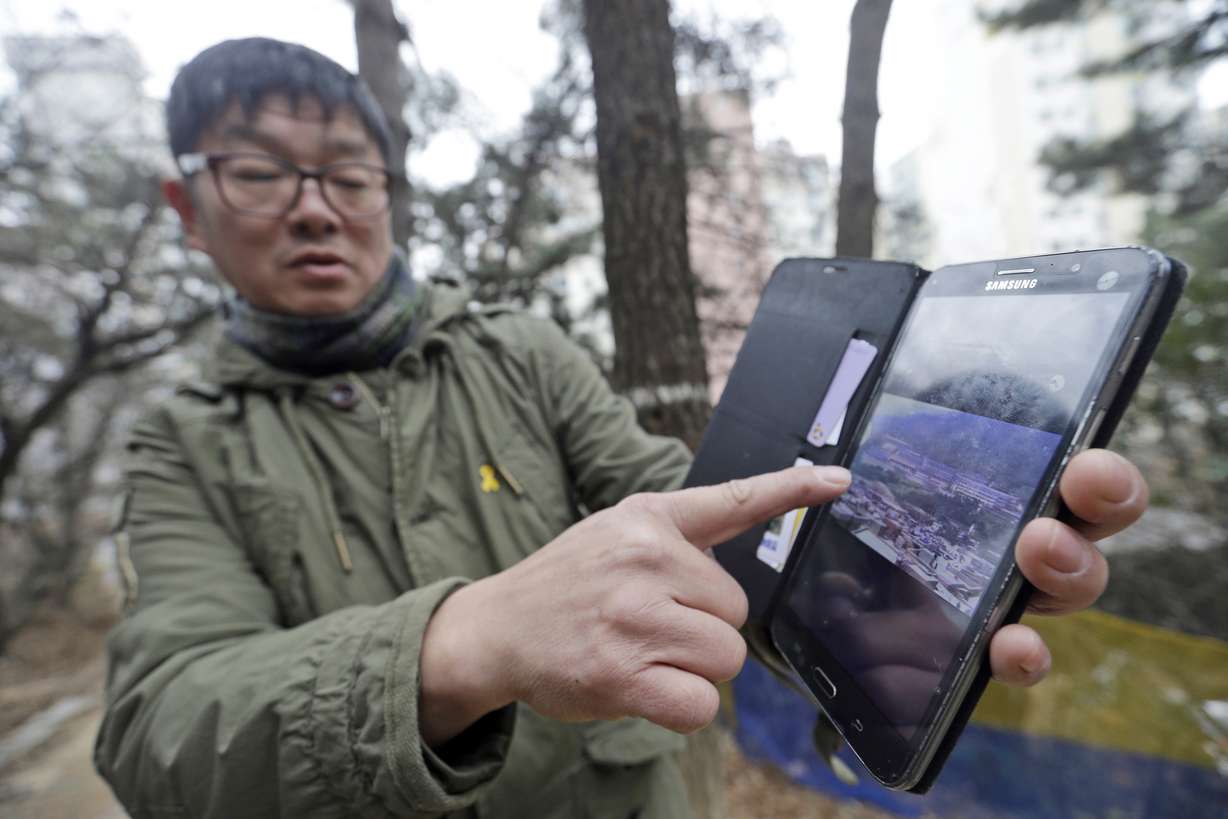 In this Jan. 28, 2016, photo, Choi Seung-woo shows an old photo of the Brothers Home, a mountainside institution where some of the worst human rights atrocities in modern South Korean history took place, in Busan, South Korea. An Associated Press investigation found that rapes and killings of children and the disabled three decades ago at a South Korean institution for so-called vagrants, the Brothers Home, were much more vicious and widespread than previously realized. (AP Photo/Ahn Young-joon)