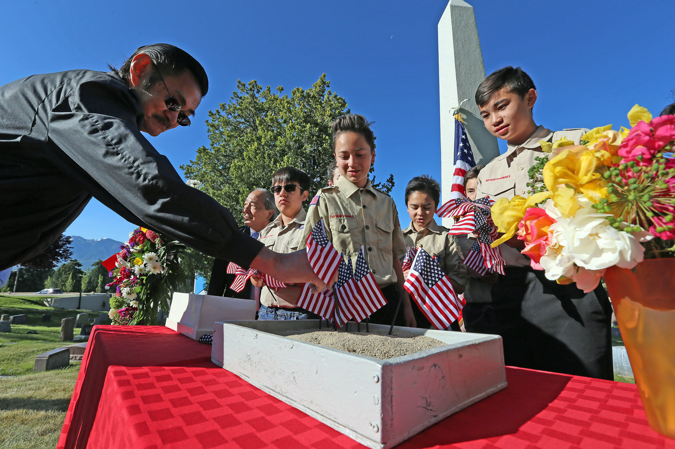 Byron Watanabe places a flag on behalf of his uncle, Russell T. Fujino, who is listed on a monument as Japanese-American veterans are remembered at a memorial service at the Salt Lake City Cemetery on Sunday, May 29, 2016. (Photo: Scott G Winterton, Deseret News)