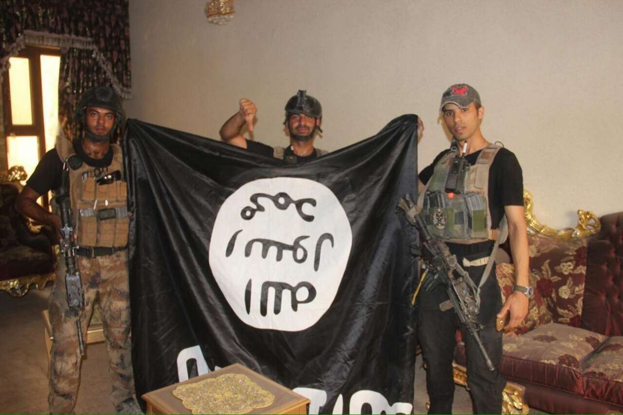 In this image taken by an Iraqi Counterterrorism Service photographer on Sunday, June 19, 2016, soldiers pose with an Islamic State militant flag in Fallujah, Iraq after forces re-took the city center after two years of IS control. Photo: AP Photo