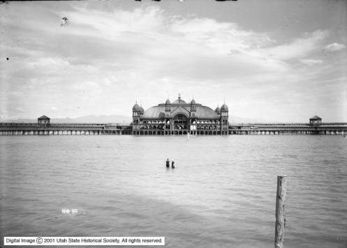 Two people standing in the shallow water in front of the main Saltair building in a photo taken sometime around 1910. (Photo: Utah Historical Society)