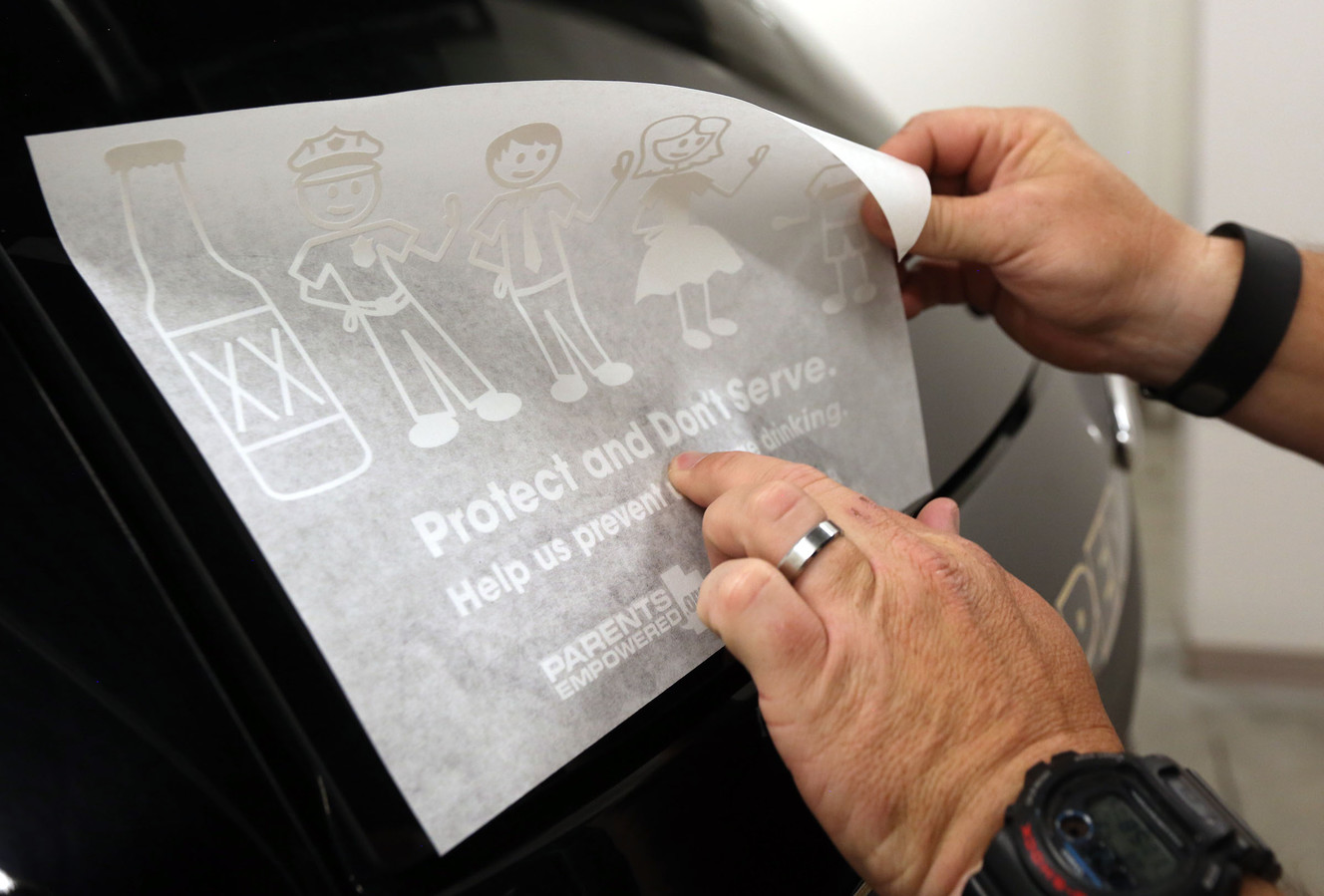 Draper Police Sgt. Chad Carpenter adheres a new underage alcohol prevention sticker to a patrol car after attending the Pledge to Prevent Underage Drinking forum in Draper on Wednesday, July 27, 2016. (Photo: Kristin Murphy, Deseret News)
