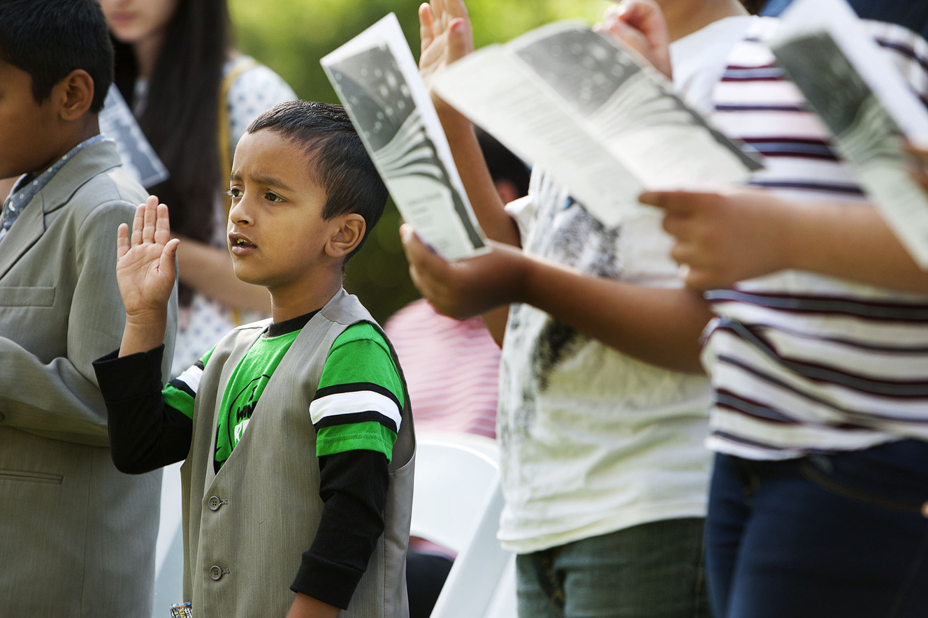 Saurav Sapkota, 6, left, raises his hand to recite the oath of allegiance at Wheeler Historic Farm in Murray, Friday, Aug. 5, 2016. U.S. Citizenship and Immigration Services presented citizenship certificates to 23 children, ages 6 to 17, during a Friday's special ceremony. (Photo: Hans Koepsell, Deseret News)