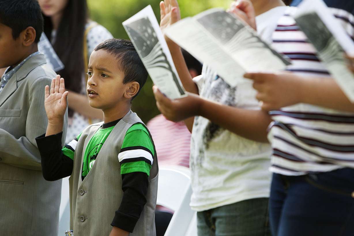 Saurav Sapkota, 6, left, raises his hand to recite the oath of allegiance at Wheeler Historic Farm in Murray, Friday, Aug. 5, 2016. U.S. Citizenship and Immigration Services presented citizenship certificates to 23 children, ages 6 to 17, during a Friday's special ceremony. (Photo: Hans Koepsell, Deseret News)