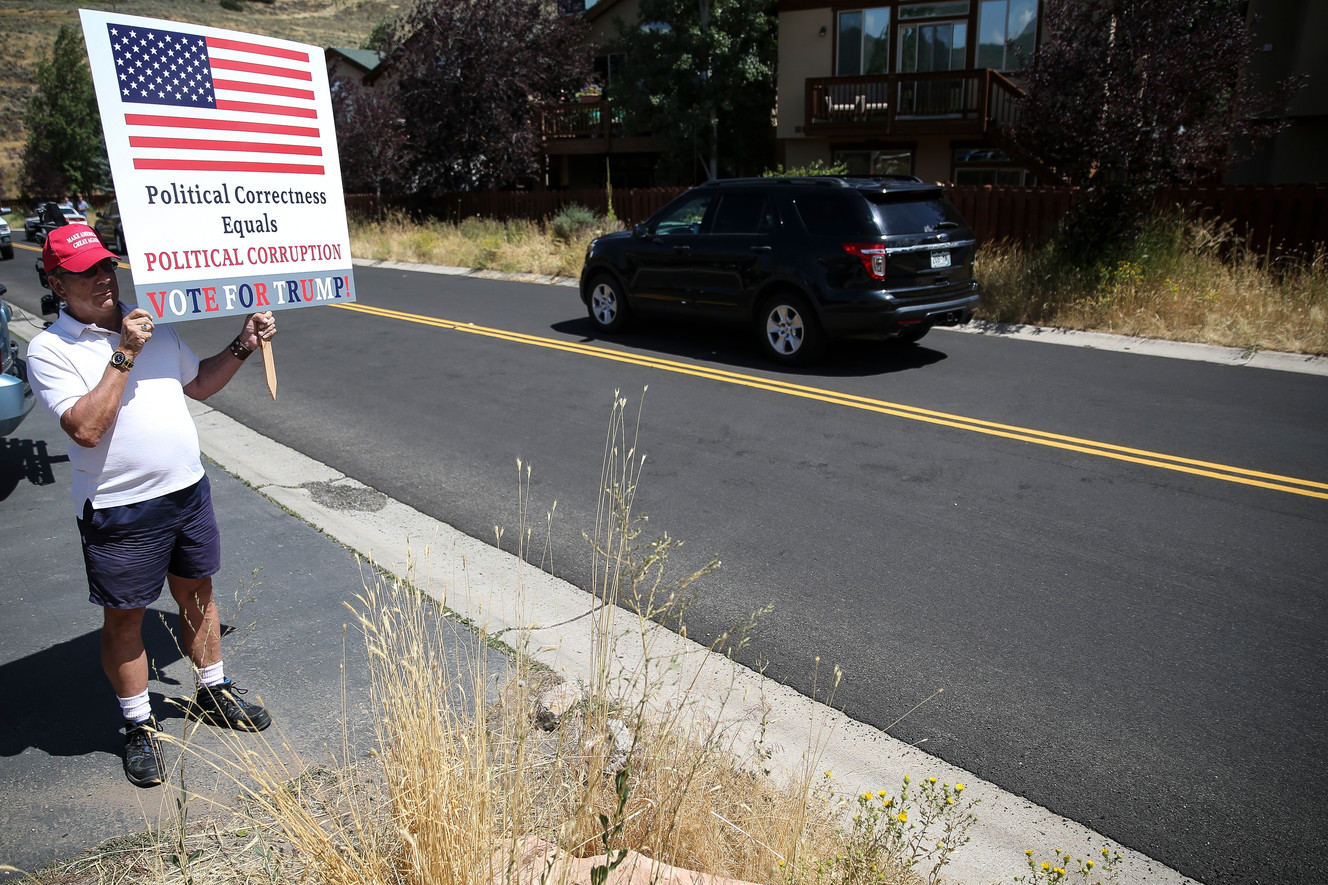 Dave Novak holds a sign as former President Bill Clinton's motorcade arrives for a fundraiser in Park City on Thursday, Aug. 11, 2016. (Photo: Spenser Heaps, Deseret News)