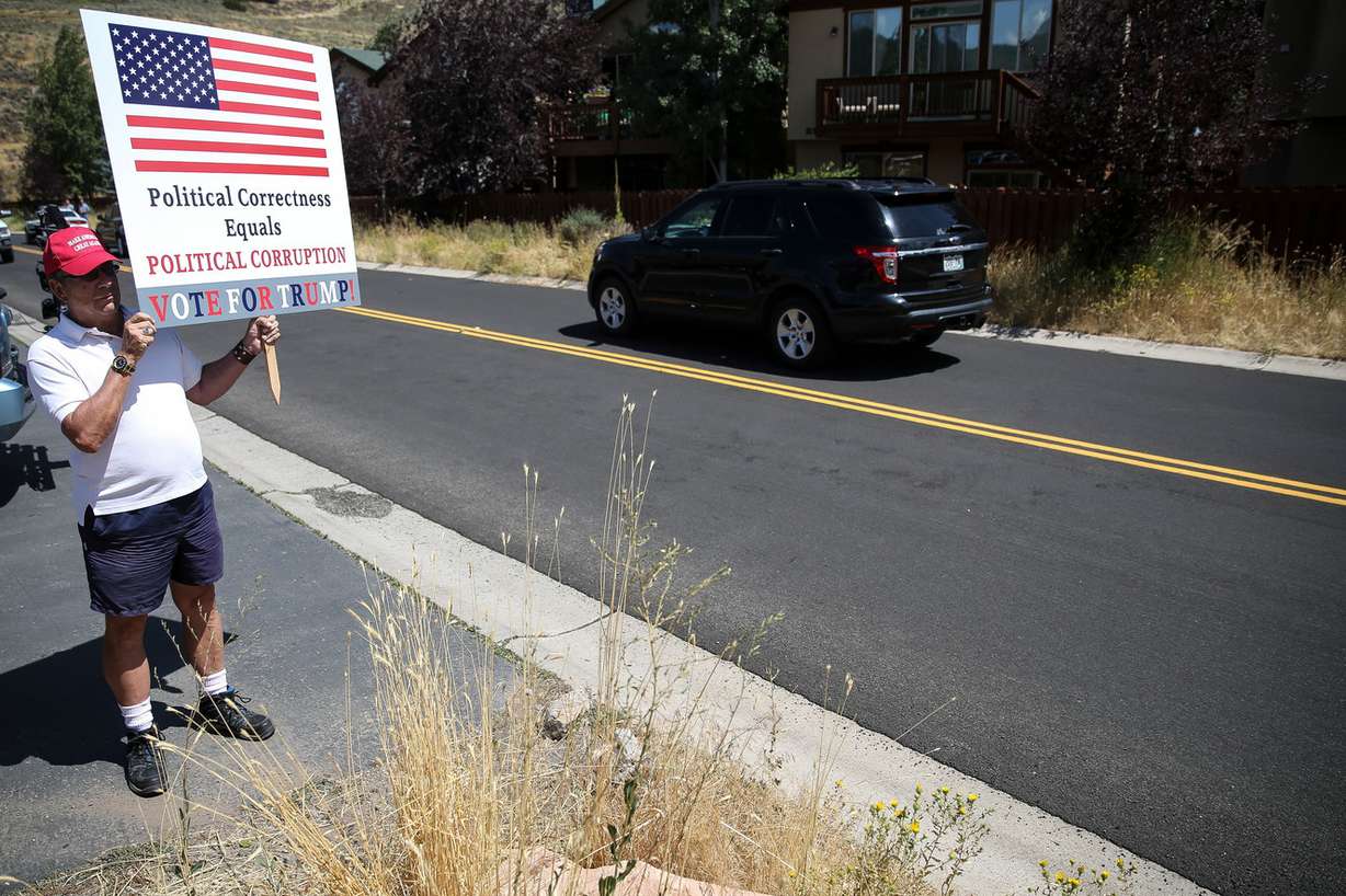 Dave Novak holds a sign as former President Bill Clinton's motorcade arrives for a fundraiser in Park City on Thursday, Aug. 11, 2016. (Photo: Spenser Heaps, Deseret News)