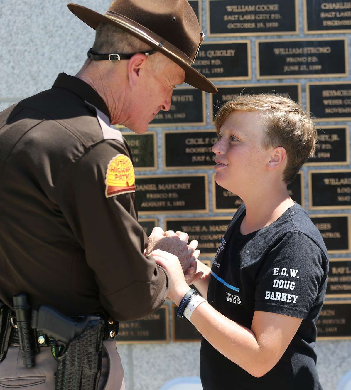 Utah Highway Patrol Col. Michael Rapich gives Jack Barney, son of fallen officer Doug Barney, his badge after a ceremony in which Salt Lake City Police Department Explorers received Explorer Memorial Guardians pins at the Utah Law Enforcement Memorial at the state Capitol on Sunday, Aug. 21, 2016. (Photo: Scott G Winterton, Deseret News)
