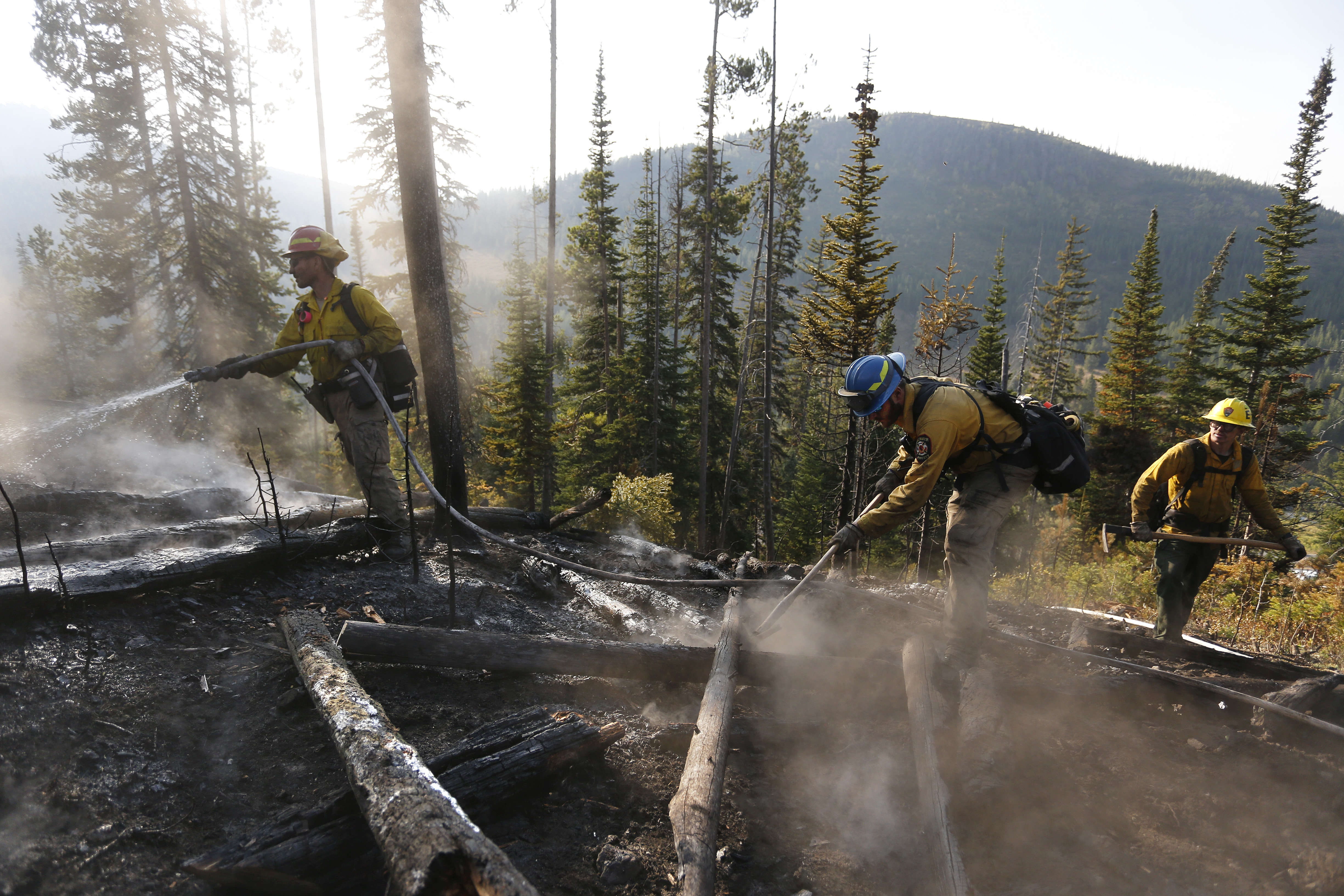 Firefighters mop up the smoking burn area of the Berry Fire near the road to Yellowstone in Grand Teton National Park, Wyo., Saturday, Aug 27, 2016. The south entrance to Yellowstone National Park is expected to remain closed for a few days due to the wildfire in Grand Teton, where firefighters are trying to clean up hotspots and burned trees along a stretch of roadway. (AP Photo/Brennan Linsley)