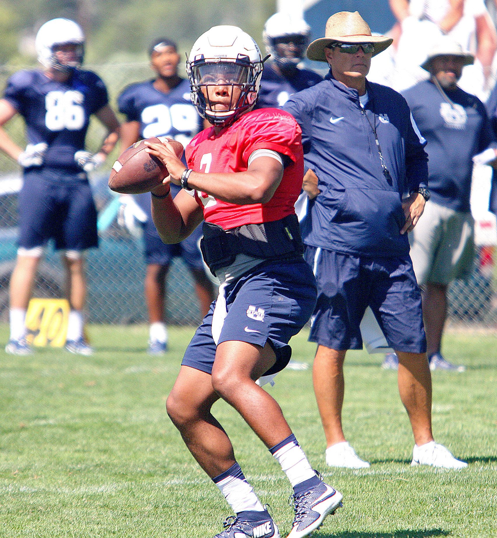 USU quarterback Kent Myers drops back to pass as assistant head coach Michael Canales looks on during an Aggie practice in Logan. (Photo: Jeff Hunter)