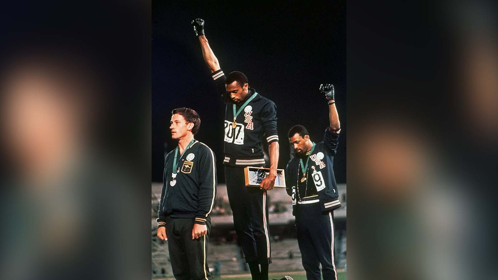 FILE - In this Oct. 16, 1968, file photo, extending gloved hands skyward in racial protest, U.S. athletes Tommie Smith, center, and John Carlos stare downward during the playing of "The Star-Spangled Banner" after Smith received the gold and Carlos the bronze medal in the 200 meter run at the Summer Olympic Games in Mexico City. (AP Photo, File)