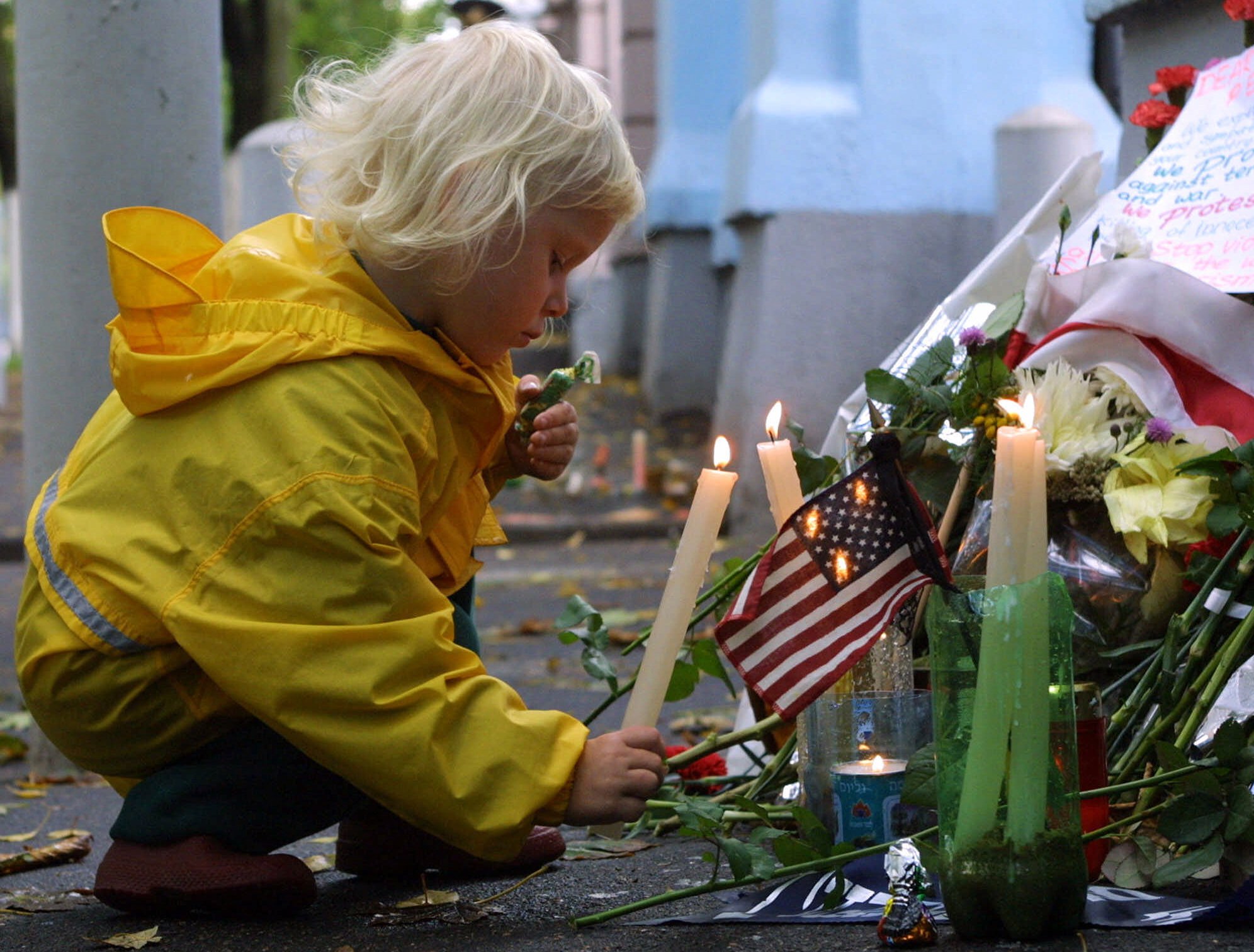 Ruzhana Vecherko, 3, puts a candle outside the U.S. Embassy in Minsk, Belarus, Wednesday, Sept 12, 2001. The poster at right reads : Dear American people, we send our condolences and sympathy to you and your country. (Sergei Grits, AP Photo)