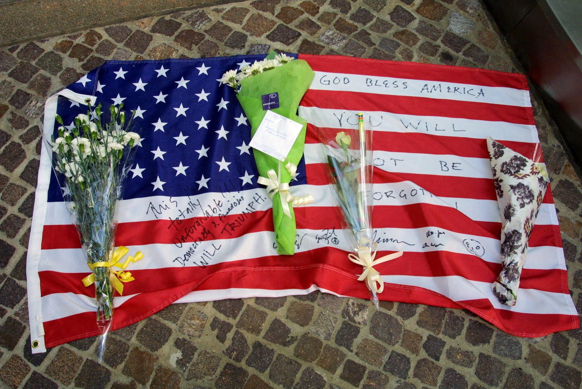 A U.S. flag laid out outside the American Consulate in Sydney, Australia, is shown Wednesday, Sept. 12, 2001. People placed flowers on the U.S. flag to commemorate victims of the terrorist attacks in New York and Washington. (Rob Griffith, AP Photo)