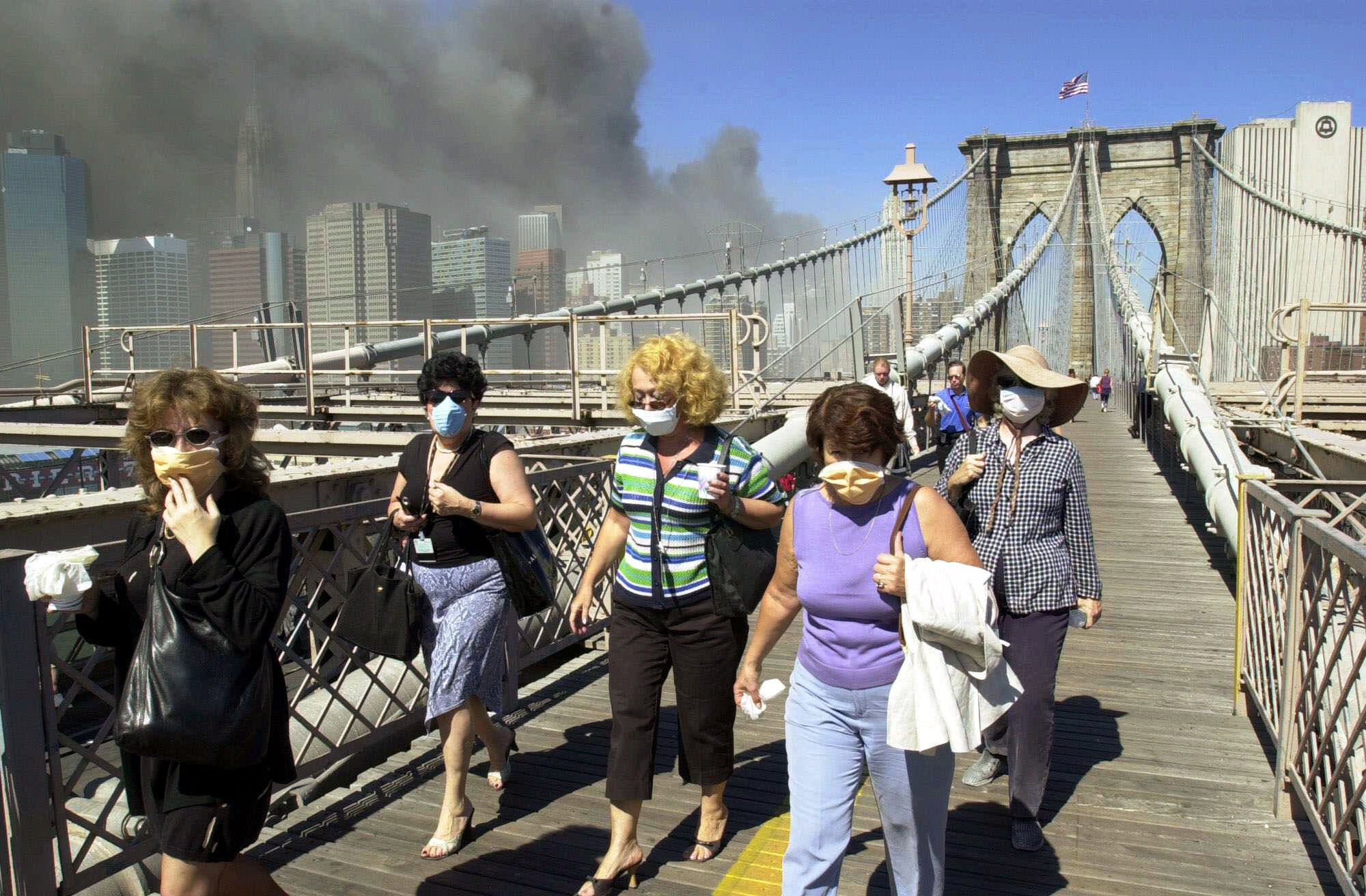 Women wearing dust masks flee across the Brooklyn Bridge from Manhattan to Brooklyn following the collapse of both World Trade Center towers Tuesday, Sept. 11, 2001 in New York. (Mark Lennihan, AP Photo)