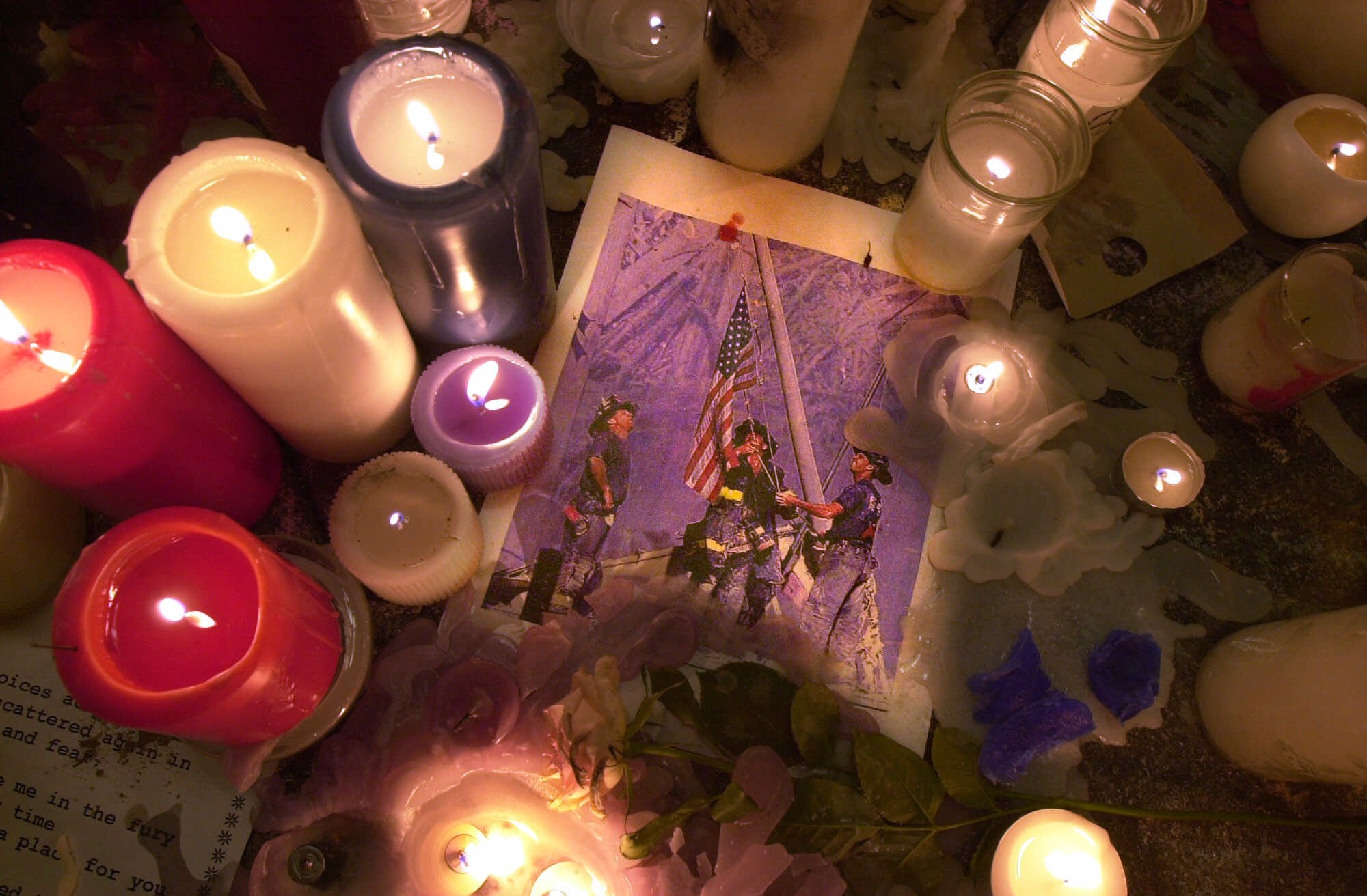 Candles at New York's Union Square park, surrounding a picture of firefighters raising an American flag at the site of Tuesday's terrorist attack against the World Trade Center, are pictured early Saturday morning, Sept. 15, 2001. (Mark Lennihan, AP Photo)