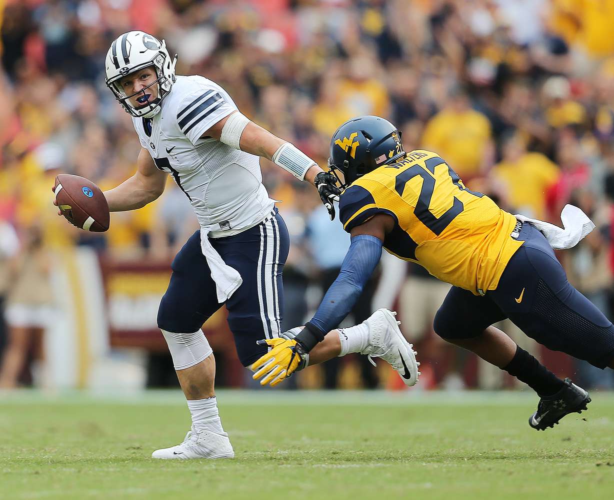 BYU quarterback Taysom Hill (7) runs away from West Virginia linebacker Sean Walters (27) play West Virginia at FedEx Field in Landover, Maryland on Saturday, Sept. 24, 2016. (Photo: Scott G Winterton, Deseret News)