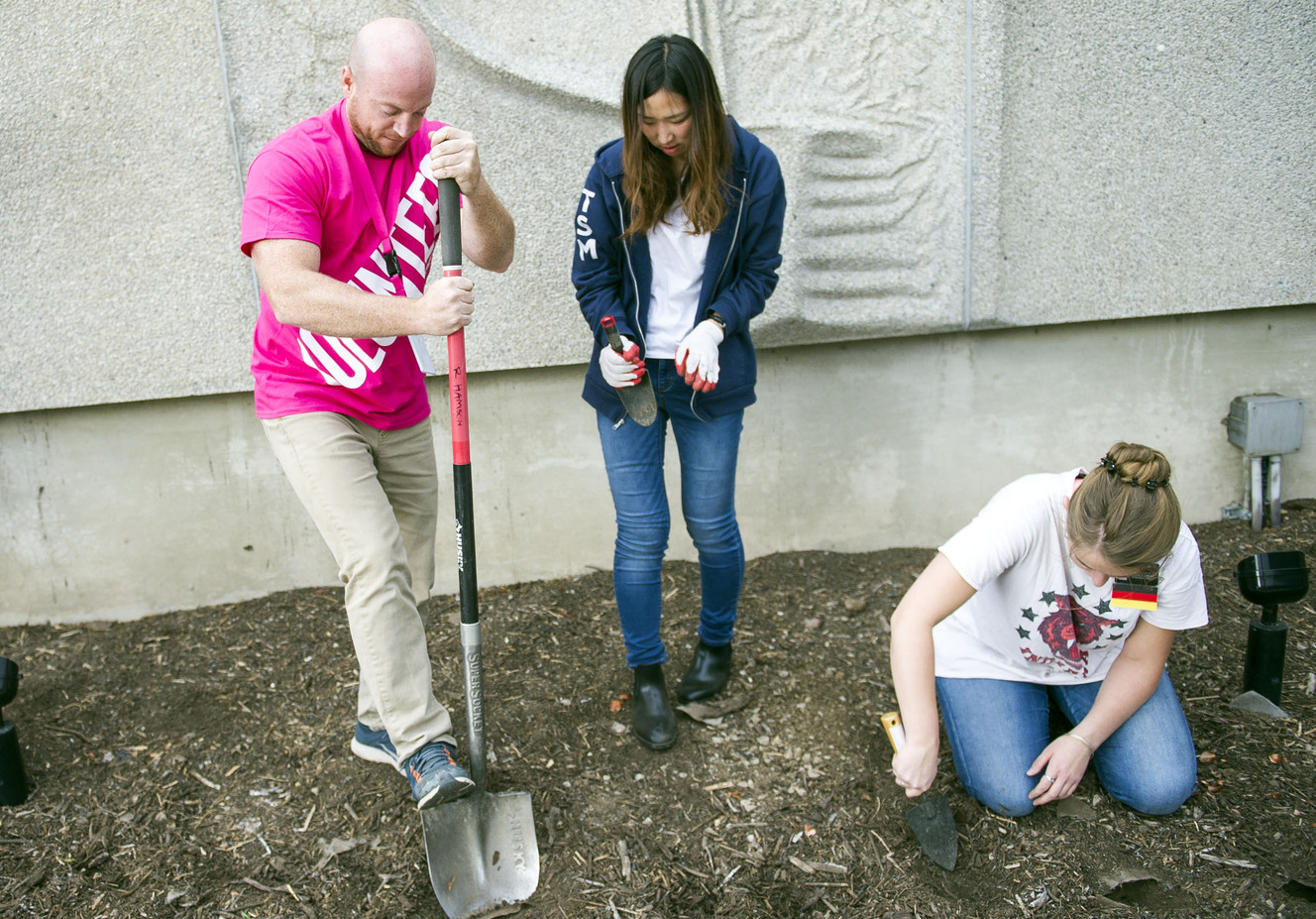Casey Petersen loosens an area of dirt for Sister Ueno, an LDS missionary from Japan, while planting tulips in honor of Breast Cancer Awareness Month outside of The Leonardo in Salt Lake City on Friday, Oct. 14, 2016. (Photo: Nick Wagner, Deseret News)