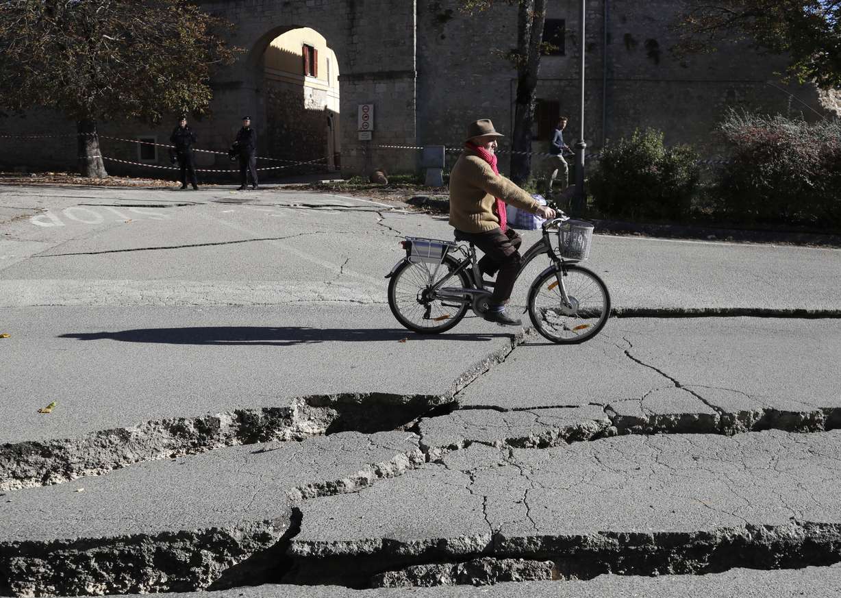 A man rides a bicycle past cracks in a road in Norcia, central Italy, after an earthquake with a preliminary magnitude of 6.6 struck central Italy, Sunday, Oct. 30, 2016. (Gregorio Borgia, AP Photo)