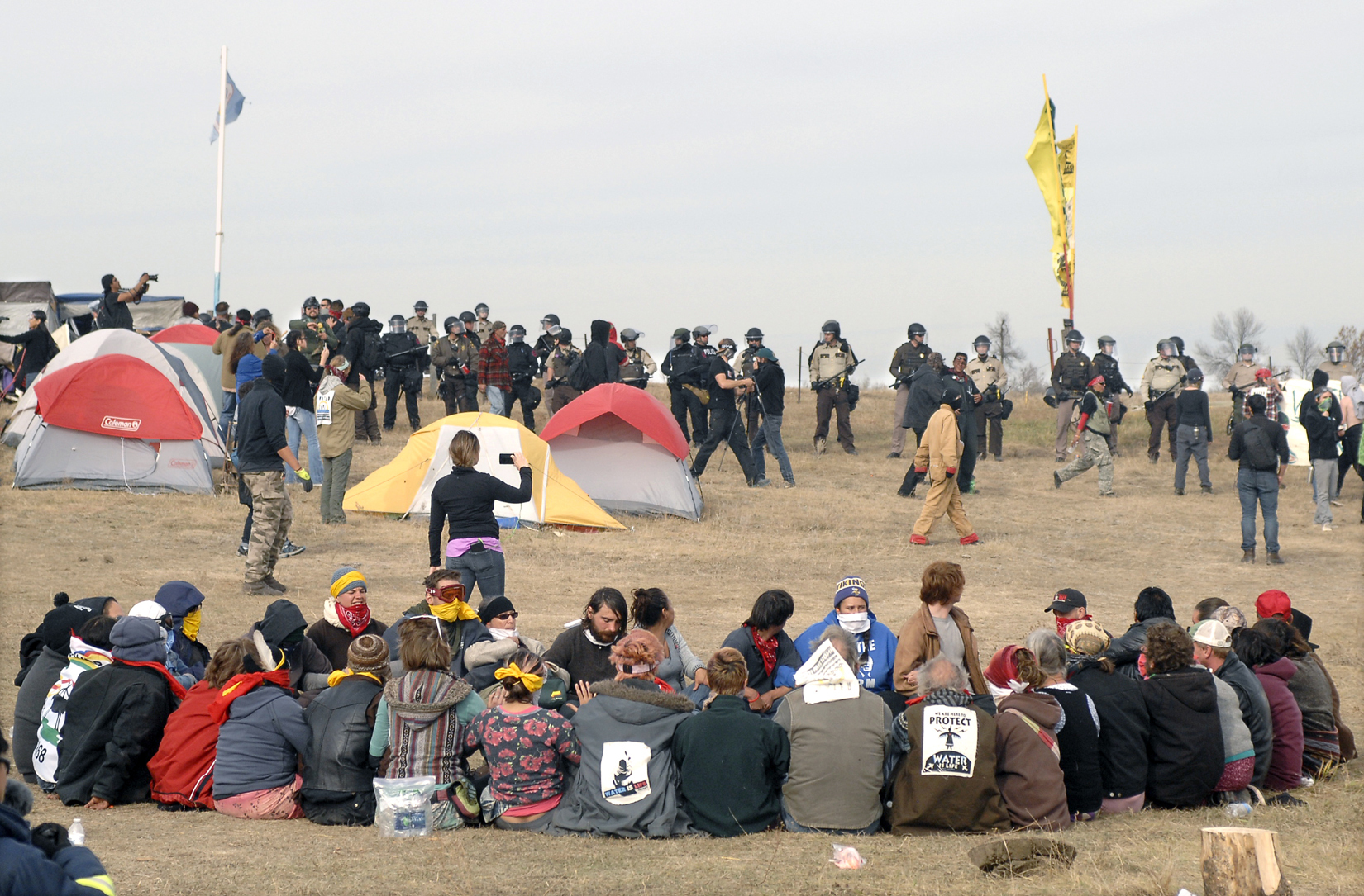 Dakota Access Pipeline protesters sit in a prayer circle at the Front Line Camp as a line of law enforcement officers make their way across the camp to remove the protesters and relocate to the overflow camp. Photo: AP Photo
