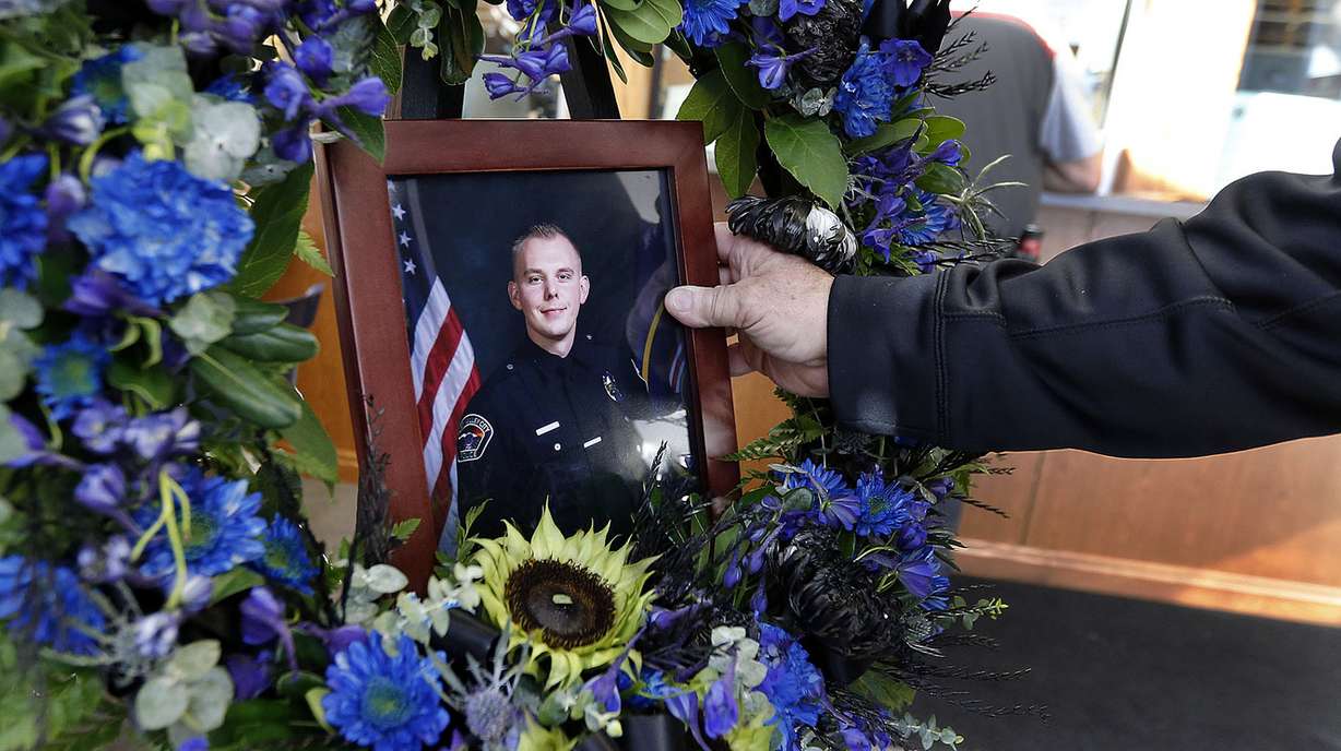 West Valley City Police Department photographer Kevin Conde places a portrait of officer Cody Brotherson in a memorial at the public safety building in West Valley City on Monday, Nov. 7, 2016. Officer Brotherson was killed while trying to help stop a fleeing car during a chase early Sunday morning. (Photo: Ravell Call, Deseret News)