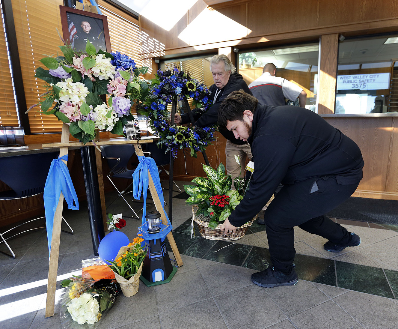 Antonio Manzano delivers flowers in West Valley City on Monday, Nov. 7, 2016, at a memorial for officer Cody Brotherson, who was killed while trying to help stop a fleeing car during a chase early Sunday morning. WVC Police Department photographer Kevin Conde sets up a new memorial display in the background. The memorial is in the WVC Public Safety building. (Photo: Ravell Call, Deseret News)