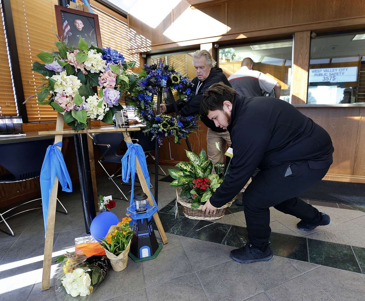 Antonio Manzano delivers flowers in West Valley City on Monday, Nov. 7, 2016, at a memorial for officer Cody Brotherson, who was killed while trying to help stop a fleeing car during a chase early Sunday morning. WVC Police Department photographer Kevin Conde sets up a new memorial display in the background. The memorial is in the WVC Public Safety building. (Photo: Ravell Call, Deseret News)