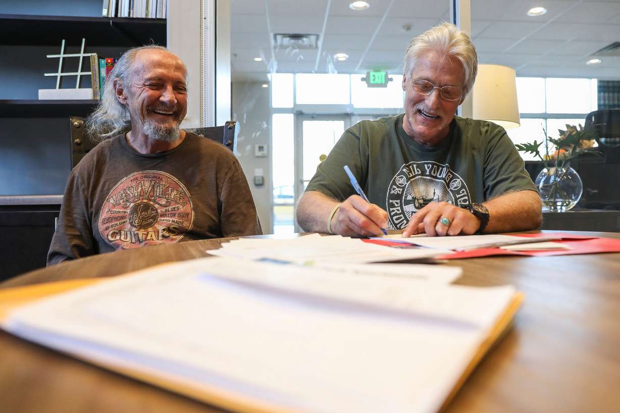 Brent Anderson, right, sits next to his friend, Dan Hughes, left, while Anderson signs a lease agreement at the Ball Park Apartments in Salt Lake City on Sunday, Nov. 6, 2016. Anderson, a formerly homeless veteran, is moving into the building through a program designed to get homeless veterans into affordable housing. (Photo: Spenser Heaps, Deseret News)