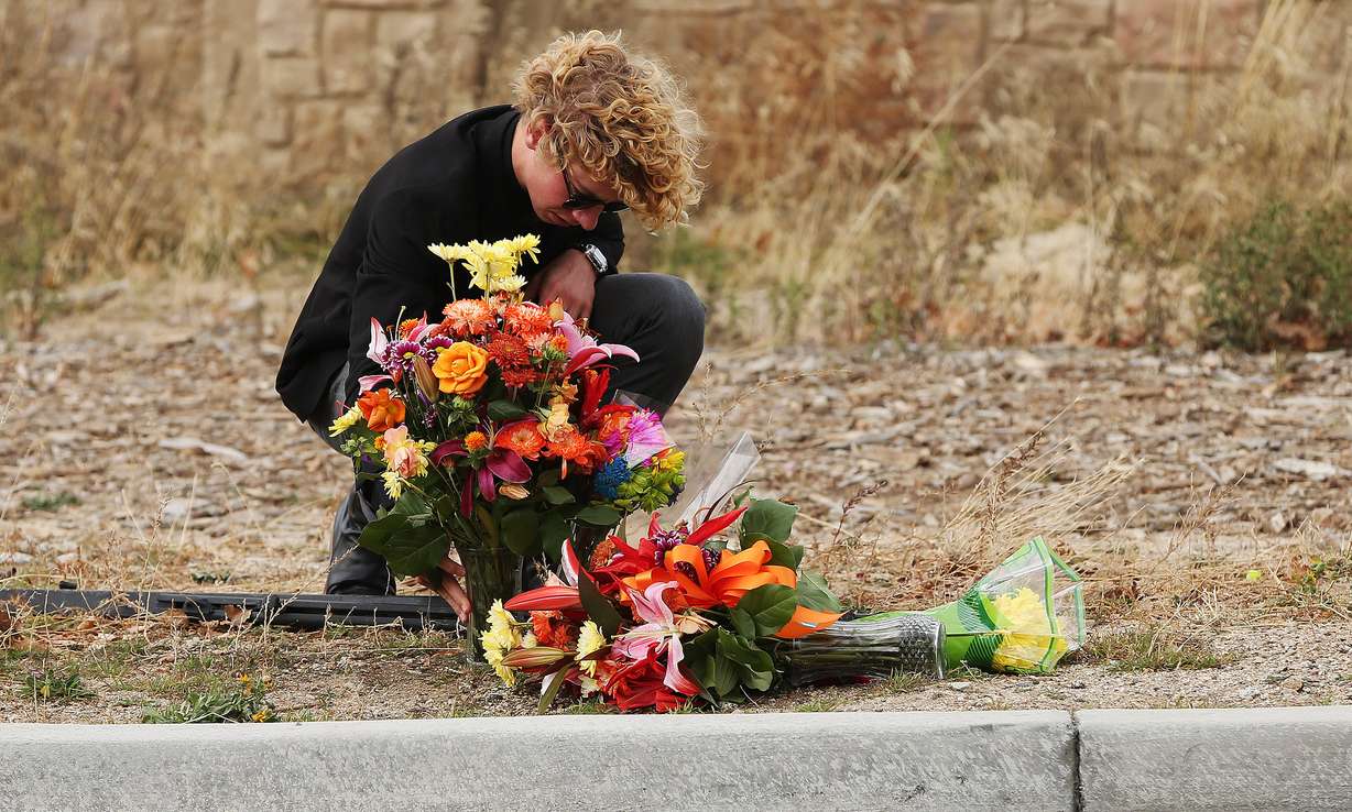Cole Hardcastle arranges flowers that were placed on the road where two juveniles were killed in an auto accident on Highland Drive in Draper on Sunday, Nov. 20, 2016. (Photo: Jeffrey D. Allred, Deseret News)