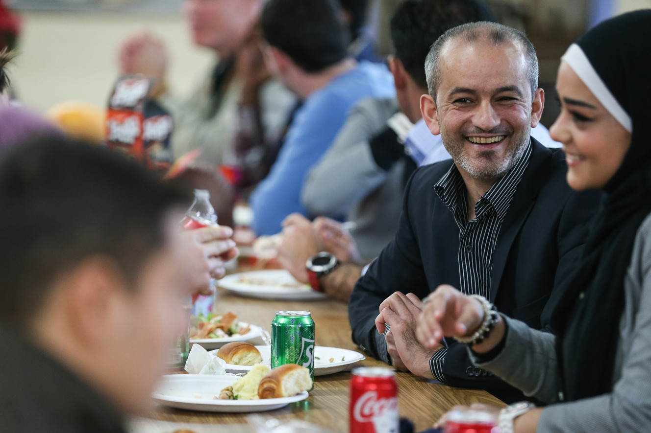 Moawiyah Bilal, second from right, and one of his daughters, Nour Bilal, right, both refugees from Syria, chat with family and friends during a Thanksgiving dinner for Syrian refugees hosted by the Catholic Community Services of Utah in Salt Lake City on Thursday, Nov. 24, 2016. (Photo: Spenser Heaps, Deseret News)