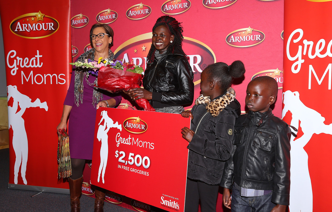 Rebecca Atem, and two of her three children, Ajoh and Nyiel Majok, are presented with a giant gift card by Marsha Gilford, vice president of public affairs at Smith's, for $2,500 as she is honored as part of the Armour “Great Moms” campaign at the YMCA in Taylorsville on Tuesday, Nov. 29, 2016. (Photo: Scott G Winterton, Deseret News)