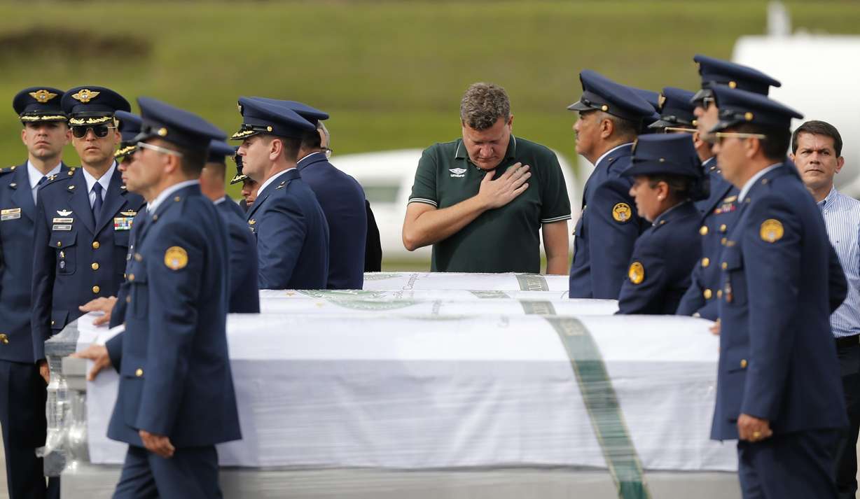 Chapeco Mayor Luciano Buligon stands with his hand over his heart as air force members and police accompany the caskets containing the remains of Brazilian victims who died in a chartered flight, to a waiting cargo plane at the military airbase in Rio Negro, Colombia, Friday, Dec. 2, 2016. The bodies are being repatriated to Chapeco, the hometown of the Brazilian soccer team whose members were on the doomed LaMia flight along with a group of journalists, headed to the Copa Sudamericana finals. (Fernando Vergara, AP Photo)