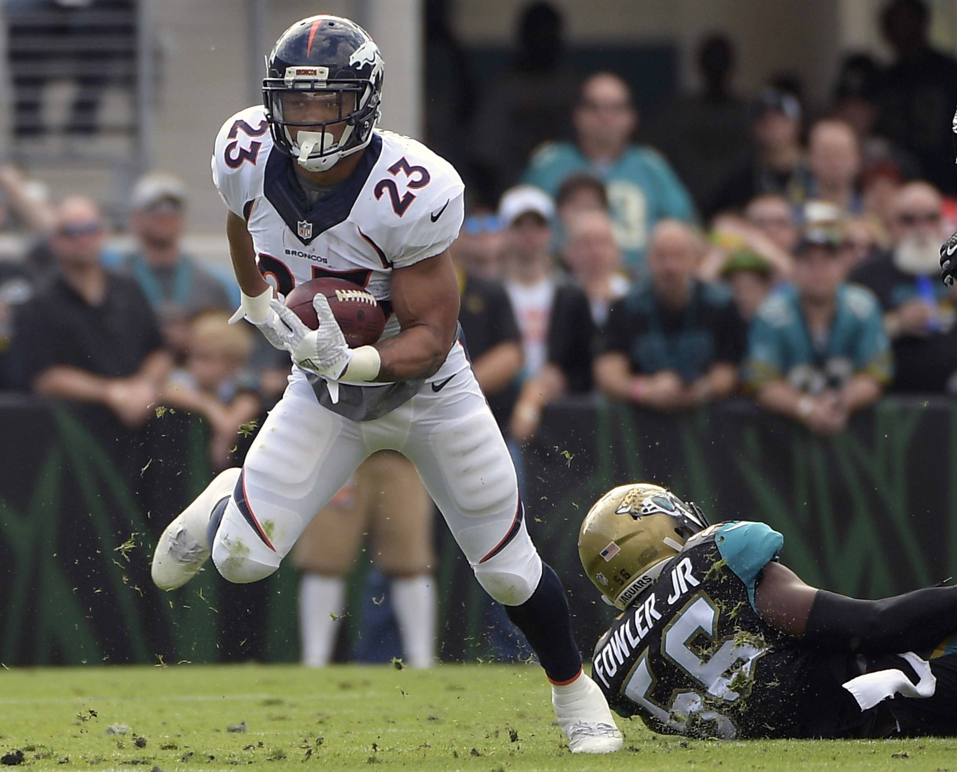 Denver Broncos' Devontae Booker (23) runs for yardage past Jacksonville Jaguars defensive end Dante Fowler (56) during the first half of an NFL football game in Jacksonville, Fla., Sunday, Dec. 4, 2016. (AP Photo, Phelan M. Ebenhack)