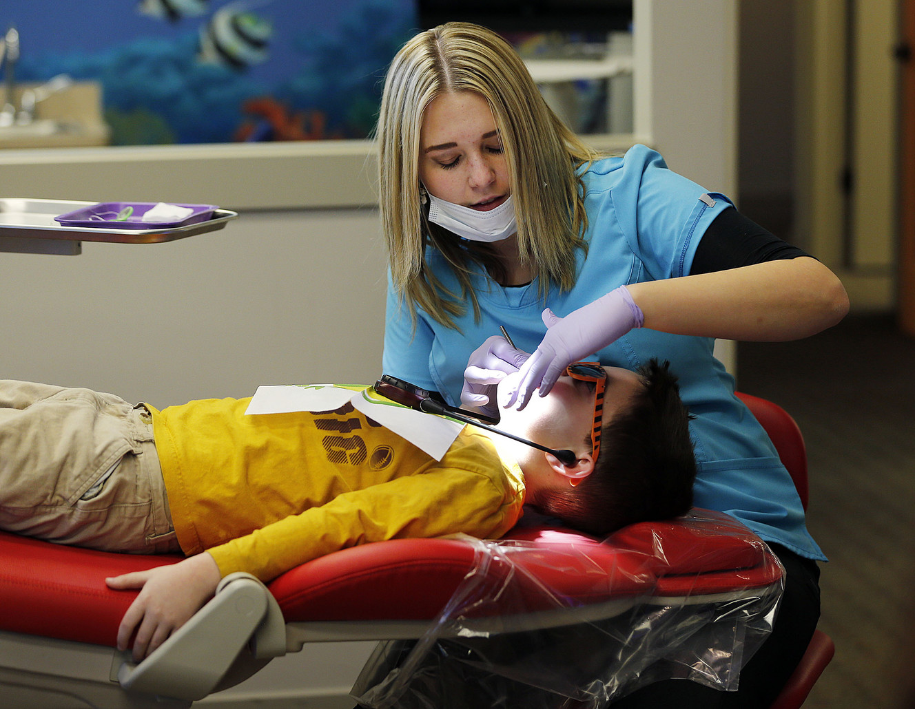 Dental assistant Celeste McHone cleans Dawson McGraw's teeth and treats them with fluoride at Kidz Dental Works in Kaysville on Dec. 5, 2016. 